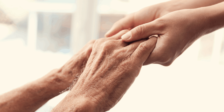 Pessoa idosa segurando a mão de um cuidador — apoio para solicitação do BPC/LOAS